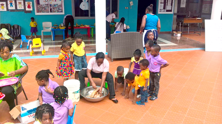 Some of the children observing how a fowl is slaughtered and chopped into pieces before the preparation of a meal.  